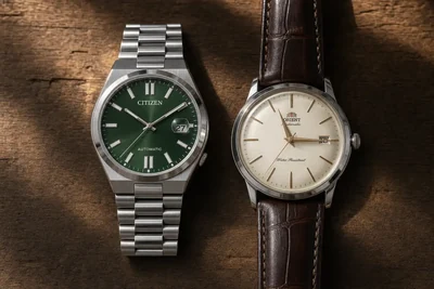 Citizen Tsuyosa de aço e Orient Bambino com pulseira de couro lado a lado sobre madeira escura