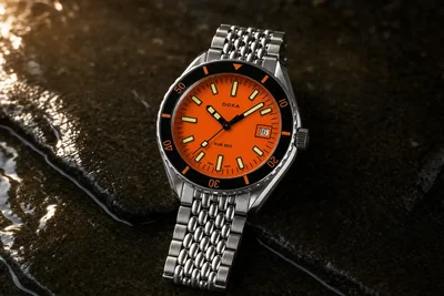 Doxa Sub 200 de mostrador laranja e bracelete de aço sobre pedra molhada