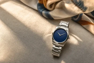 Relógio de mostrador azul e bracelete de aço sobre linho claro