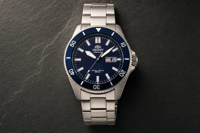 Orient Kanno de mostrador azul e bracelete de aço sobre pedra escura