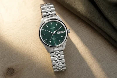 Timex Legacy de mostrador verde e caixa de aço sobre madeira clara, com data