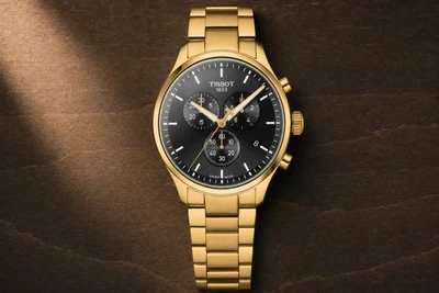 Tissot Chrono XL de mostrador preto e bracelete de aço sobre mesa escura