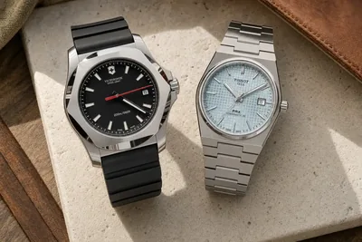 Victorinox I.N.O.X. e Tissot PRX lado a lado sobre pedra clara